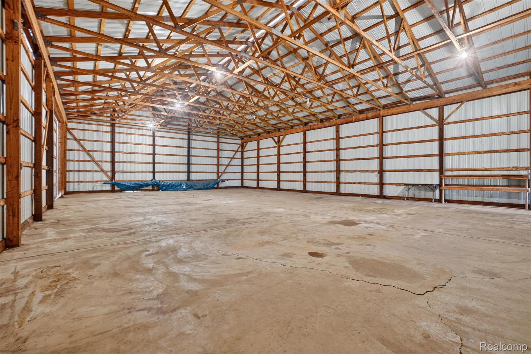 3760 Webberville Road North Williamston, MI 48895 - Photo 53 of 80 Expansive interior structure with a concrete floor, exposed wood beam ceiling, and corrugated metal walls