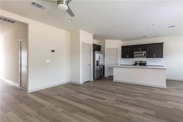 a view of kitchen with stainless steel appliances kitchen island wooden floor and living room view