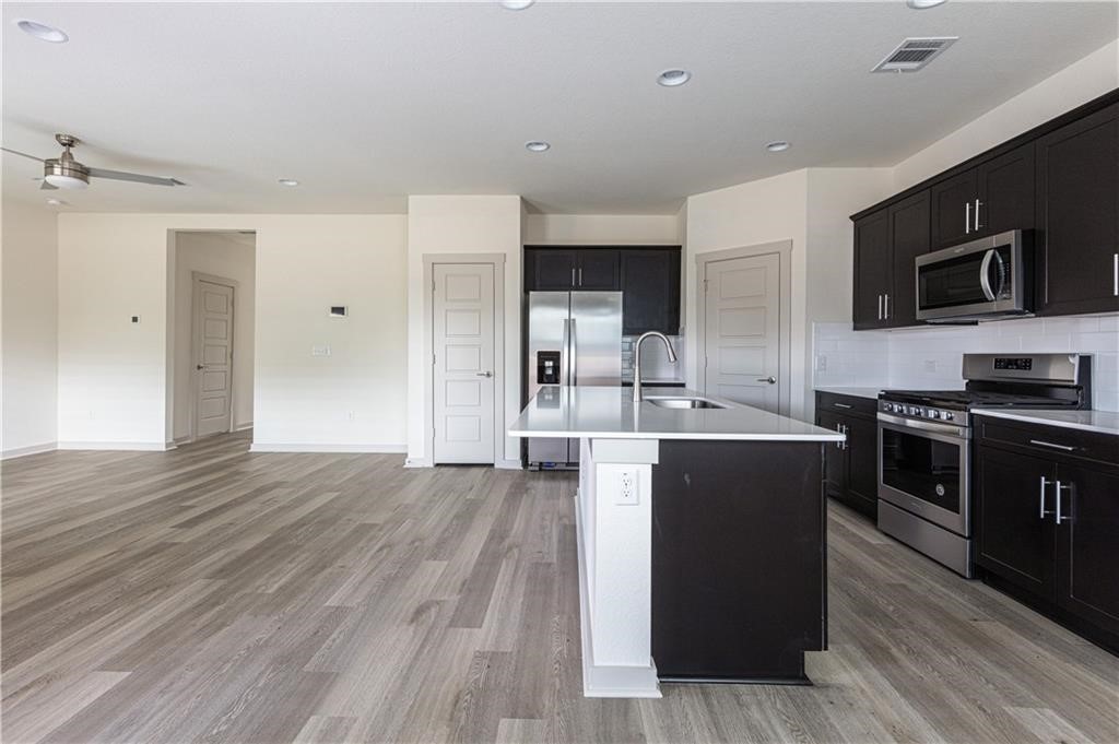 1801 Bonham Lane Round Rock, TX 78664 - Photo 7 of 24 a kitchen with stainless steel appliances kitchen island granite countertop a stove a sink and a refrigerator