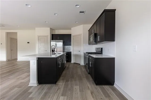 a kitchen with stainless steel appliances granite countertop a stove a sink and a microwave