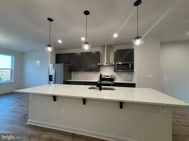 a kitchen with kitchen island a counter top a stove a sink dishwasher and a wooden cabinets
