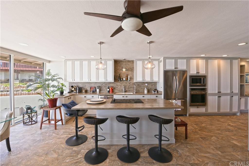 106 Blue Lagoon Laguna Beach, CA 92651 - Photo 10 of 46 a kitchen with stainless steel appliances kitchen island granite countertop a table chairs and a refrigerator