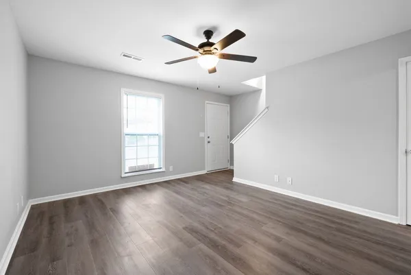 an empty room with wooden floor and windows
