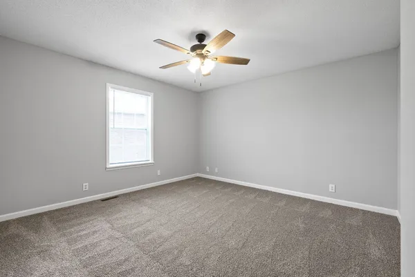 an empty room with window and ceiling fan