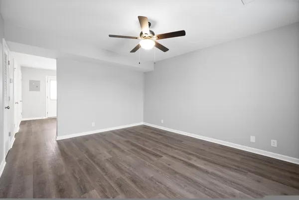 a view of an empty room with wooden floor and a ceiling fan