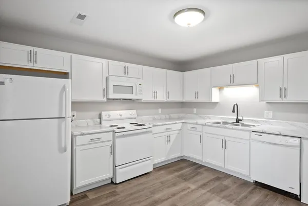 a kitchen with a sink a refrigerator and white cabinets