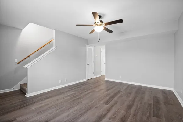 a view of an empty room with wooden floor and a ceiling fan