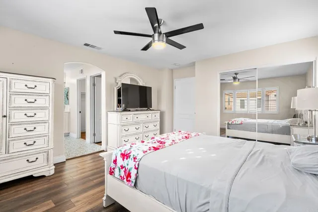 a bedroom with a bed a dresser and flat screen tv