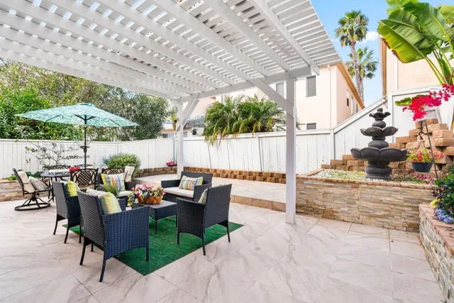 a view of a patio with couches and table and chairs under an umbrella with a barbeque