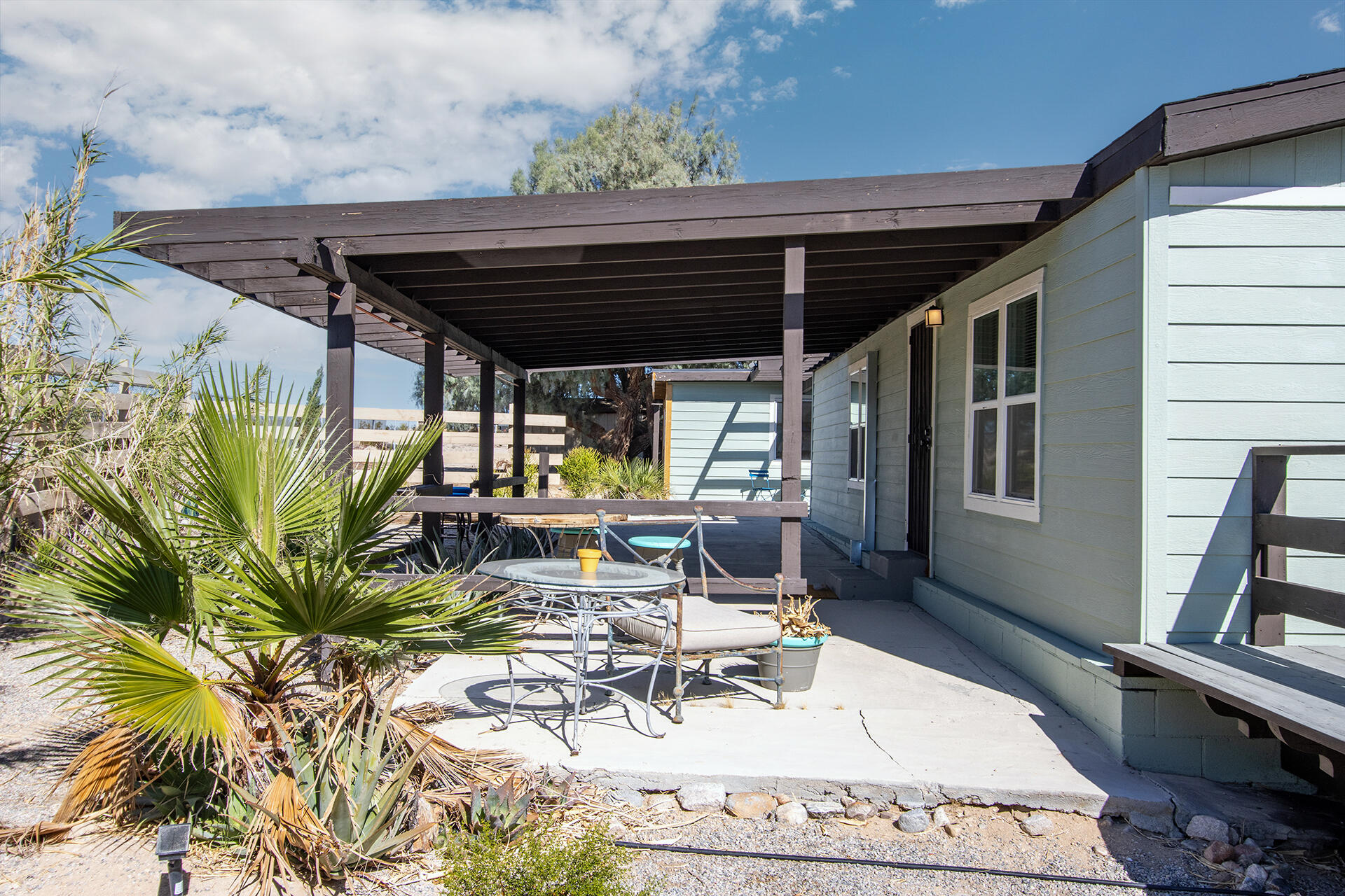 66621 Daisy Lane Joshua Tree, CA 92252 - Photo 26 of 53 a view of a patio with table and chairs potted plants with wooden floor and fence