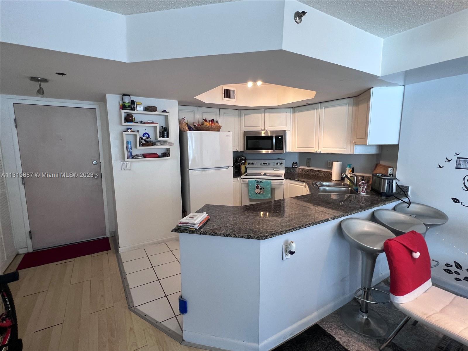 8911 Collins Avenue, Unit 1004 Surfside, FL 33154 - Photo 12 of 20 a kitchen with stainless steel appliances granite countertop a sink refrigerator and stove