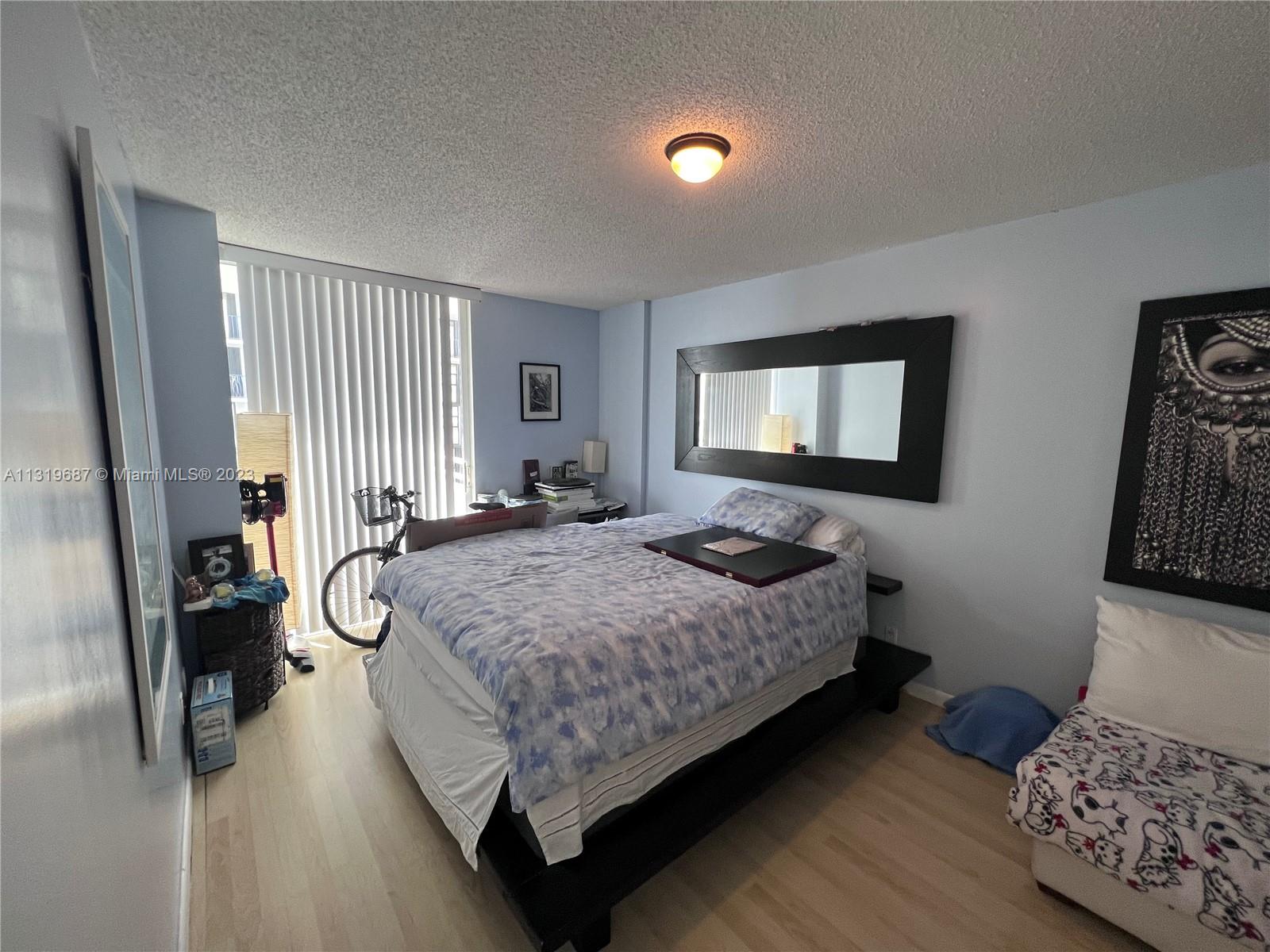 8911 Collins Avenue, Unit 1004 Surfside, FL 33154 - Photo 13 of 20 a bedroom with a bed and a dresser next to a window