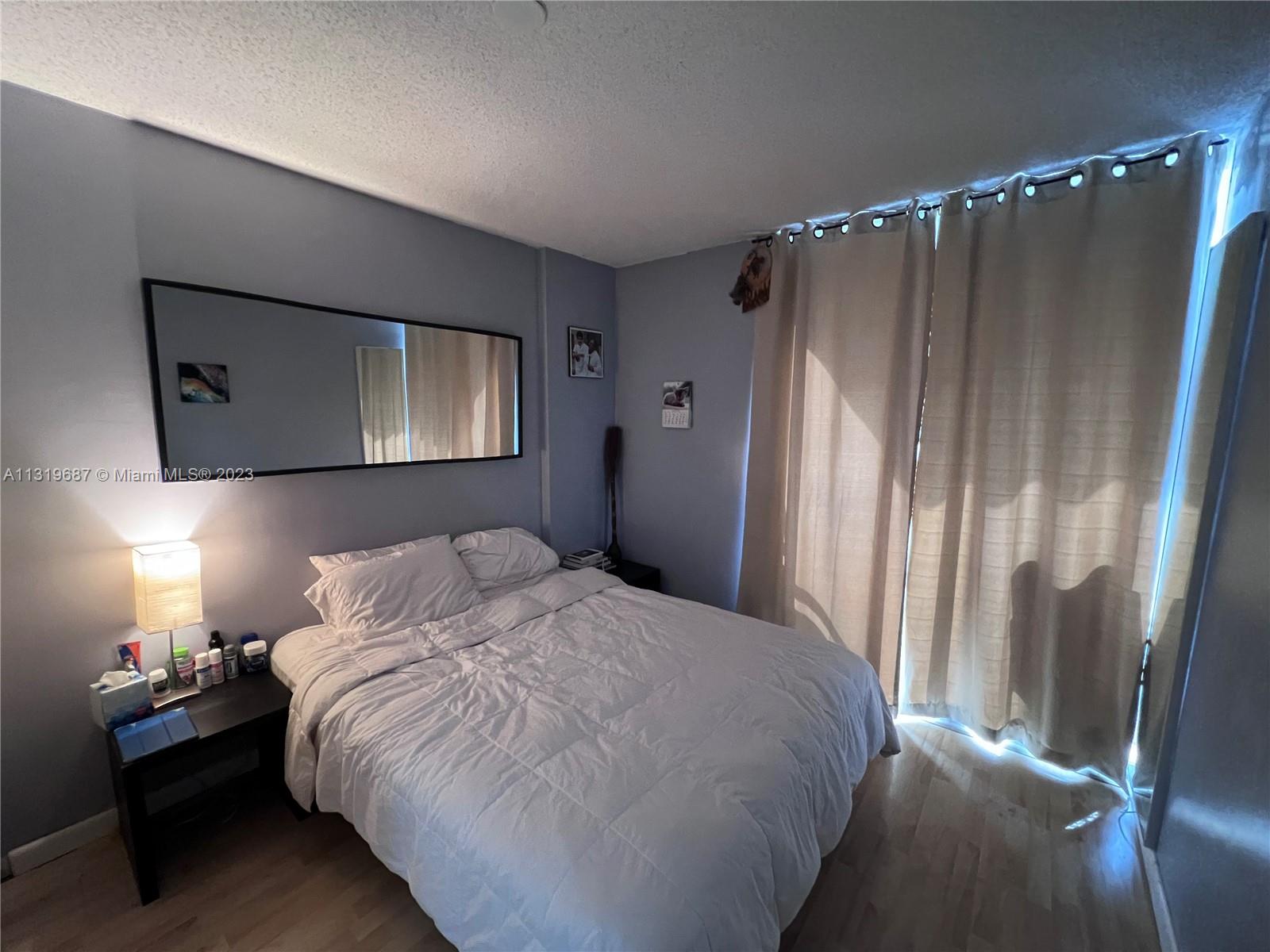 8911 Collins Avenue, Unit 1004 Surfside, FL 33154 - Photo 17 of 20 a bedroom with a bed and a mirror