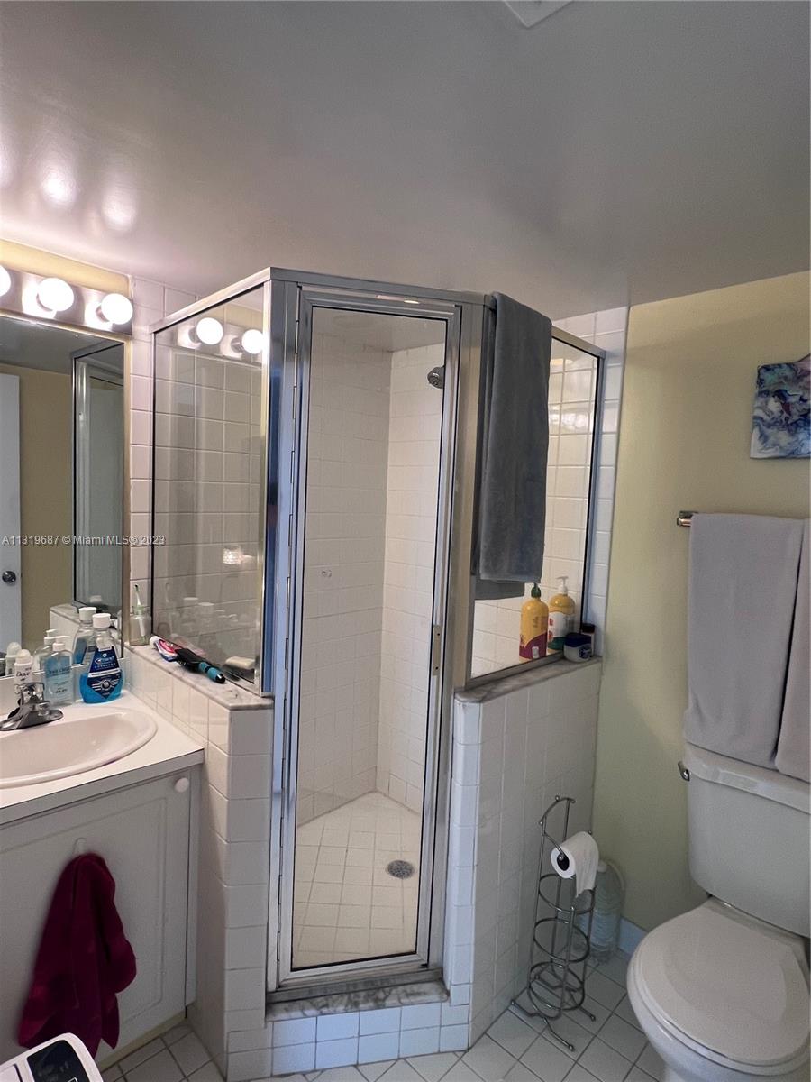 8911 Collins Avenue, Unit 1004 Surfside, FL 33154 - Photo 18 of 20 a bathroom with a sink a toilet a mirror and shower