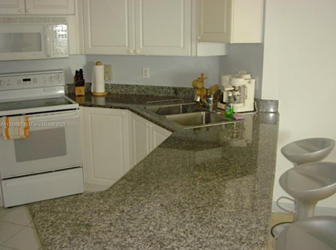 8911 Collins Avenue, Unit 1004 Surfside, FL 33154 - Photo 9 of 20 a kitchen with a sink and cabinets