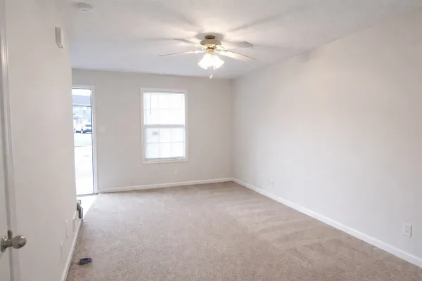 an empty room with windows and chandelier fan
