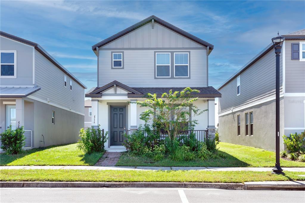 a view of a house with brick walls plants and large tree