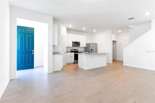 a view of a kitchen with refrigerator and white cabinets