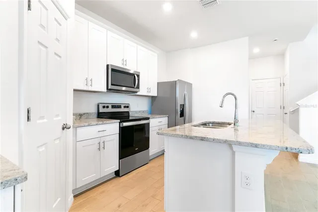 a kitchen with stainless steel appliances granite countertop a refrigerator stove a sink and a microwave