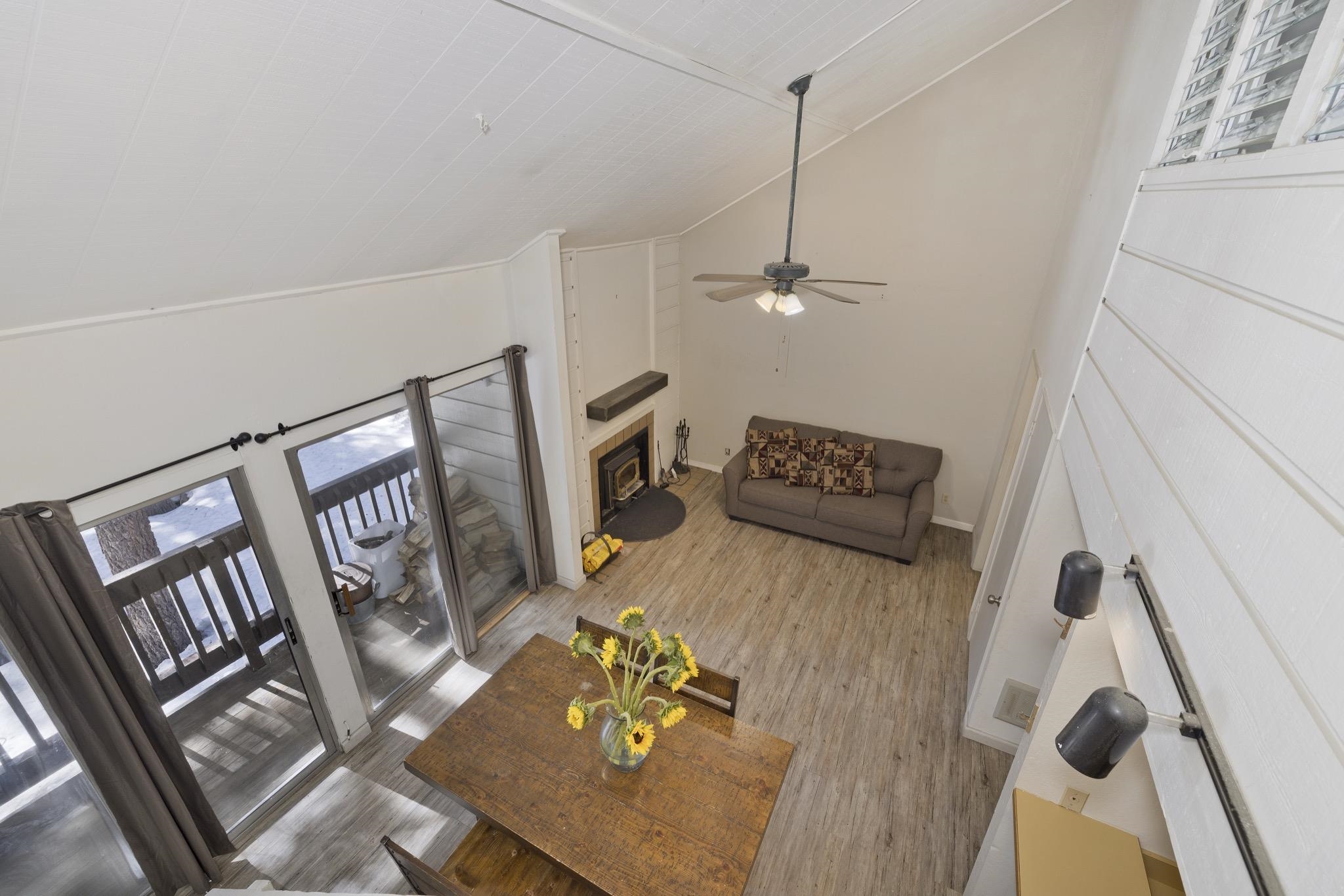 Living room featuring a fireplace with flush hearth, a ceiling fan, lofted ceiling, and light wood-style floors