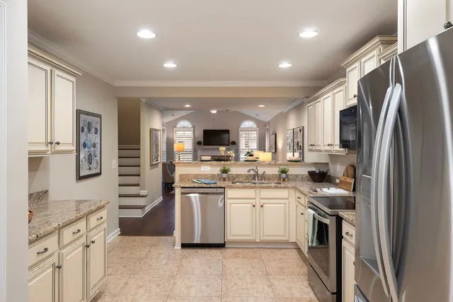 a kitchen with stainless steel appliances kitchen island granite countertop a refrigerator and a stove top oven