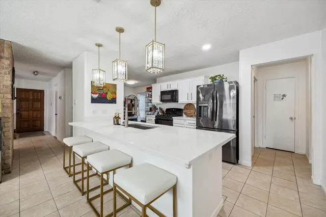 a large kitchen with stainless steel appliances kitchen island granite countertop a table chairs and a refrigerator