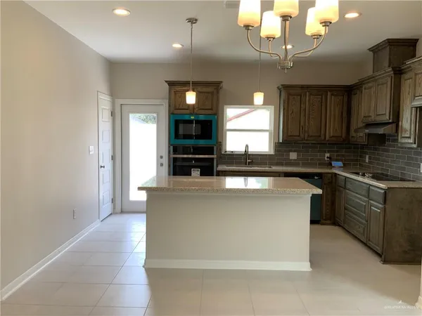 a view of kitchen with kitchen island granite countertop a refrigerator and a stove top oven