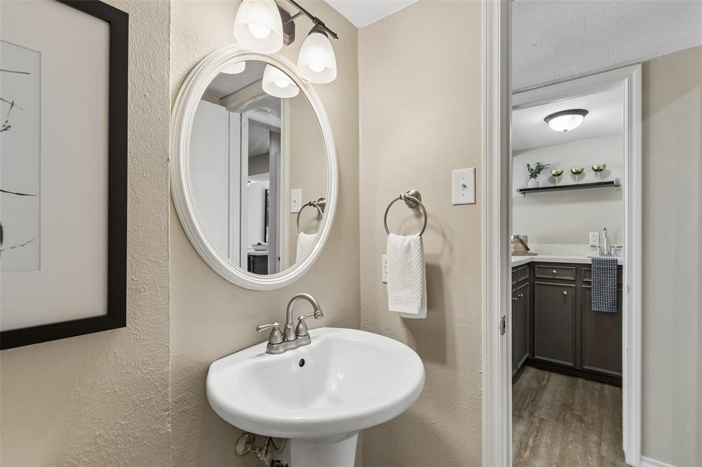 4962 Thunder Road Dallas, TX 75244 - Photo 10 of 26 The powder bath features a pedestal sink and easy access to the living and kitchen areas.