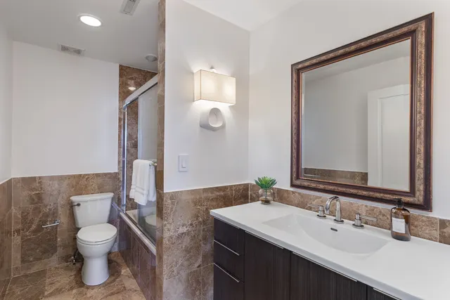 a bathroom with a granite countertop sink a toilet and a mirror
