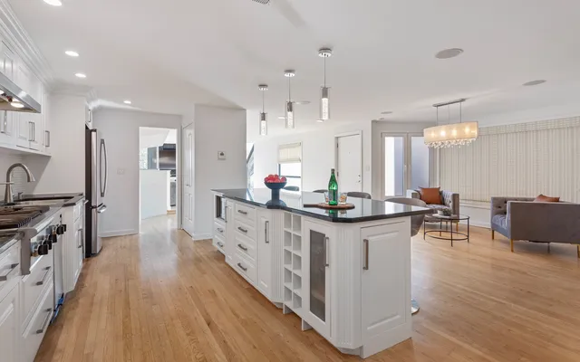 a large kitchen with stainless steel appliances a stove a sink dishwasher and a dining table with wooden floor