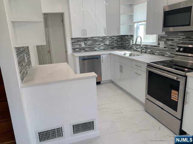 279 Slocum Way Fort Lee, NJ 07024 - Photo 5 of 20 a kitchen with stainless steel appliances a stove a sink and a refrigerator