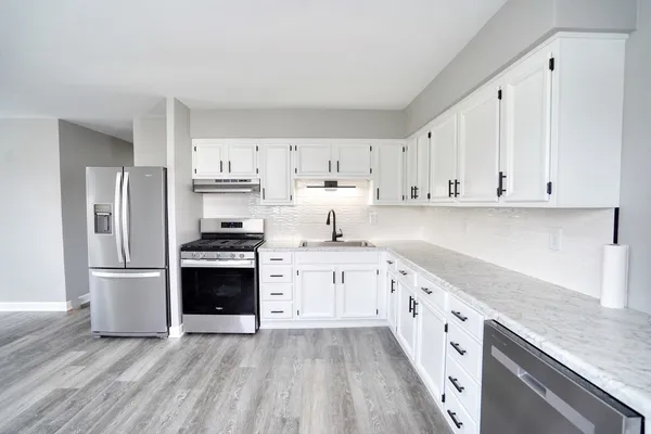 a kitchen with granite countertop white cabinets and stainless steel appliances