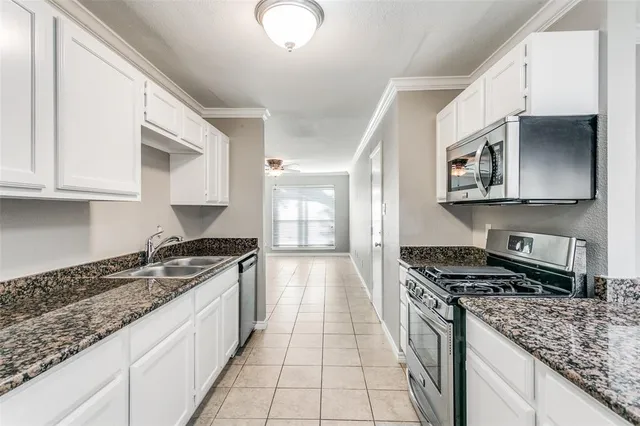a kitchen with granite countertop a refrigerator and a stove top oven