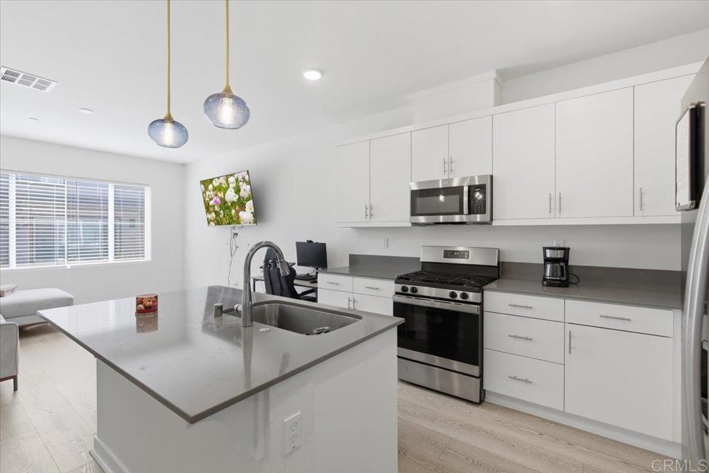 35180 Grove Trail Fallbrook, CA 92028 - Photo 9 of 23 a kitchen with stainless steel appliances granite countertop a sink a stove a microwave a sink a refrigerator white cabinets and a window