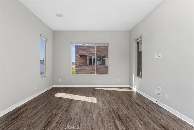 a view of a big room with wooden floor and windows