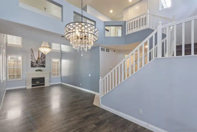 a view of an empty room with wooden floor fireplace and a window