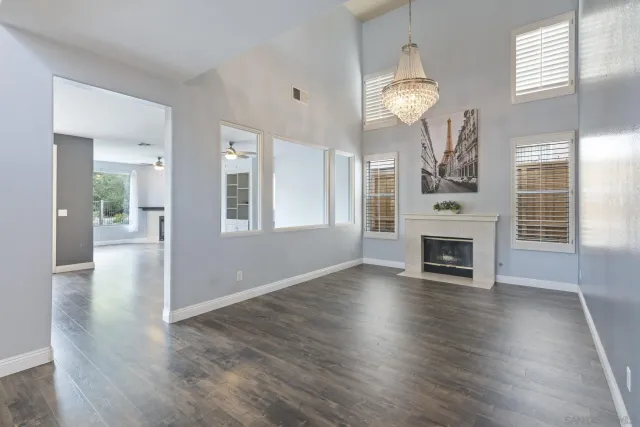 a view of an empty room with wooden floor and a fireplace
