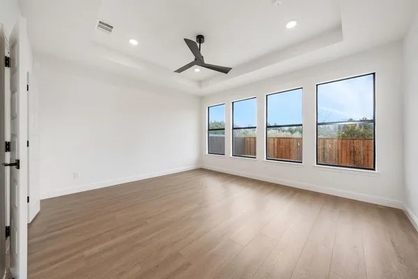 an empty room with wooden floor and windows