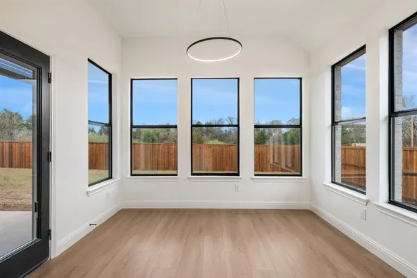 a view of an empty room with a window and wooden floor