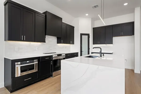a kitchen with stainless steel appliances a stove a microwave and white cabinets