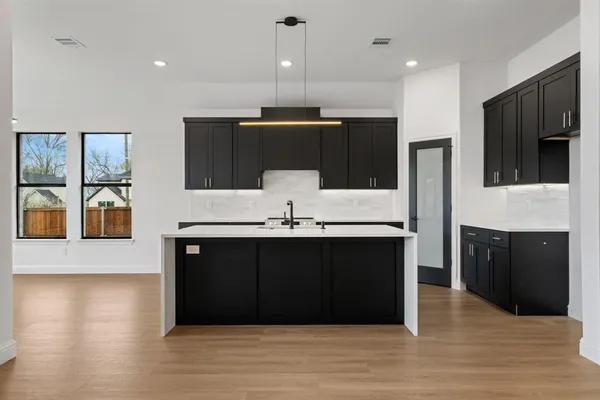 a kitchen with a sink and a stove top oven with wooden floor