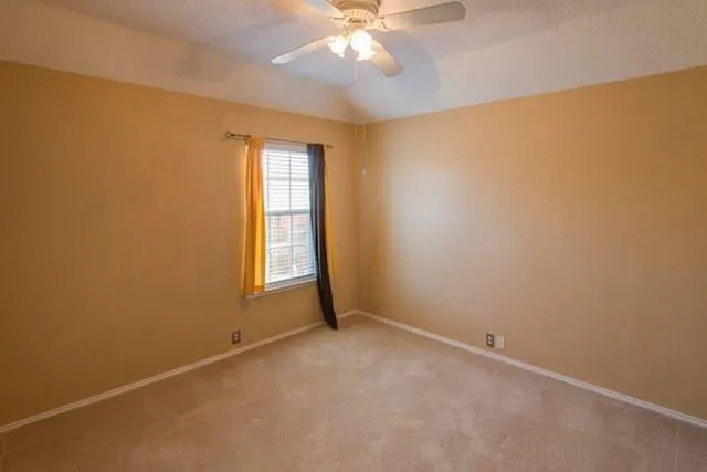 an empty room with a chandelier fan and windows