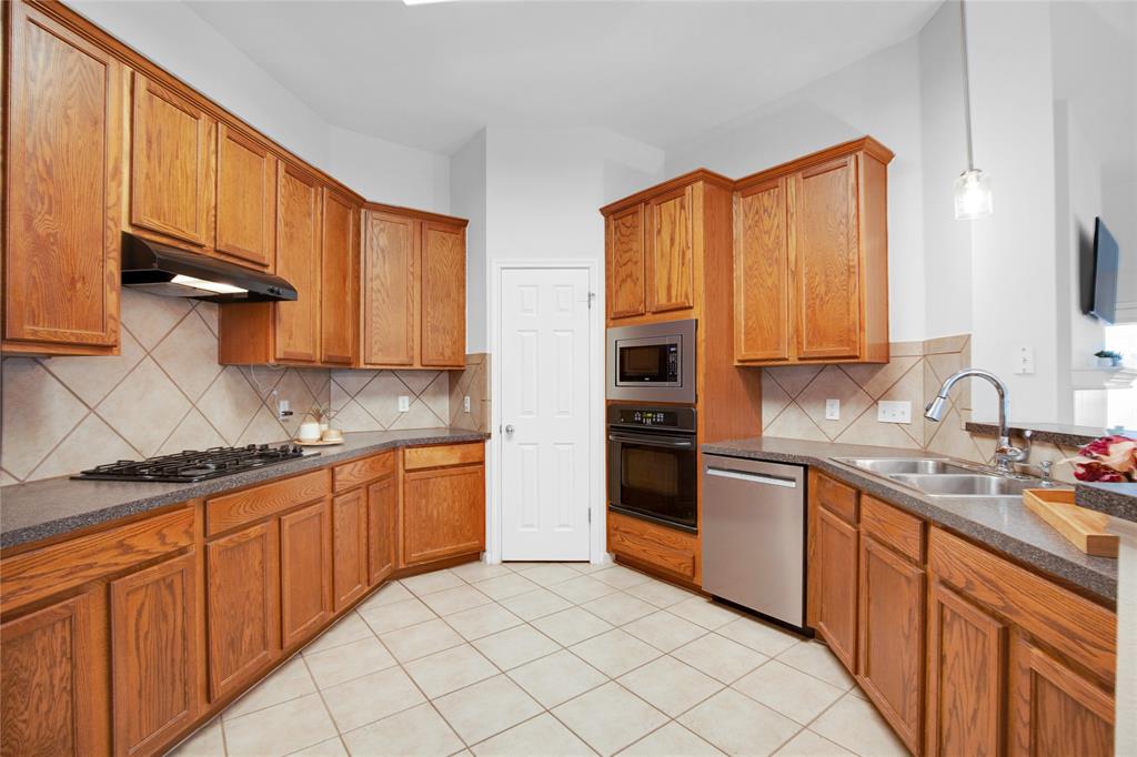 281 Hutton Kyle, TX 78640 - Photo 17 of 37 A warm-toned kitchen with abundant cabinetry, featuring modern stainless steel appliances and durable tile flooring.