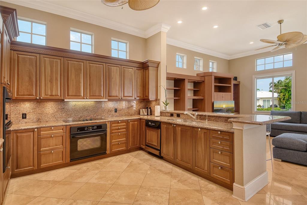 591 Putting Green Lane Longboat Key, FL 34228 - Photo 23 of 68 a kitchen with stainless steel appliances granite countertop a stove top oven a sink dishwasher and cabinets with wooden floor