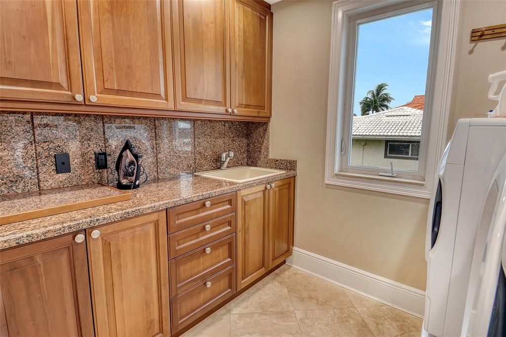 591 Putting Green Lane Longboat Key, FL 34228 - Photo 54 of 68 a kitchen with stainless steel appliances granite countertop a sink a stove and a refrigerator with wooden cabinets