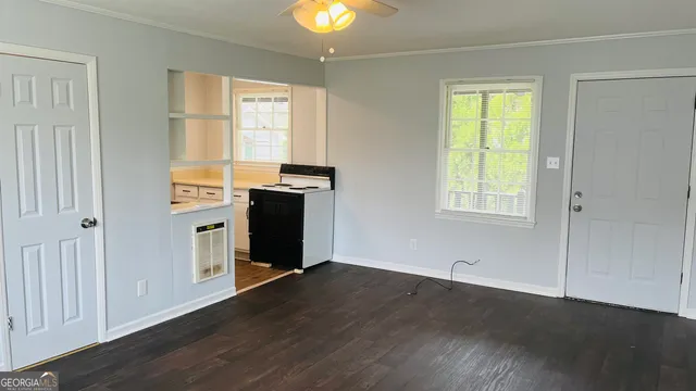 an empty room with wooden floor closet and windows