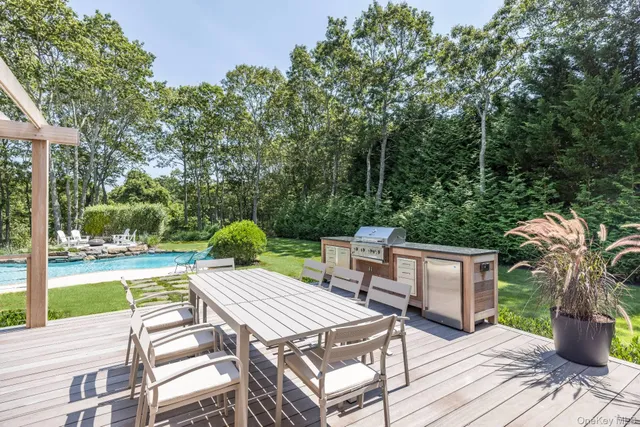 a view of a patio with a dining table and chairs with wooden floor and fence