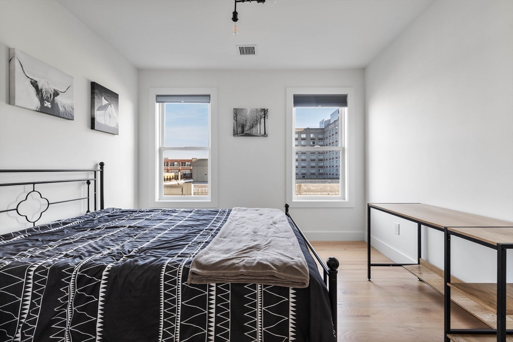 161 Cottage Street, Unit 9 Boston, MA 02128 - Photo 19 of 26 a bedroom with a bed and a dresser with wooden floor