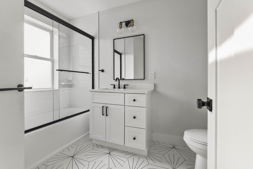 161 Cottage Street, Unit 9 Boston, MA 02128 - Photo 22 of 26 a bathroom with a granite countertop sink toilet and mirror