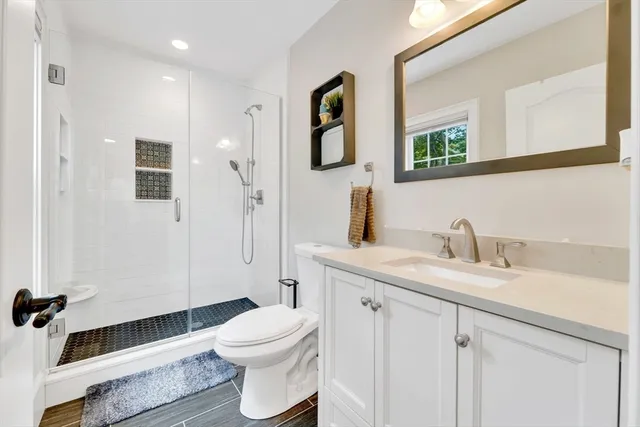 a bathroom with a granite countertop sink toilet a mirror a vanity and shower